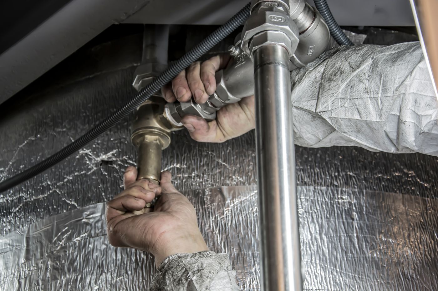 Plumber tightening the P-trap under a kitchen sink in Tacoma, WA